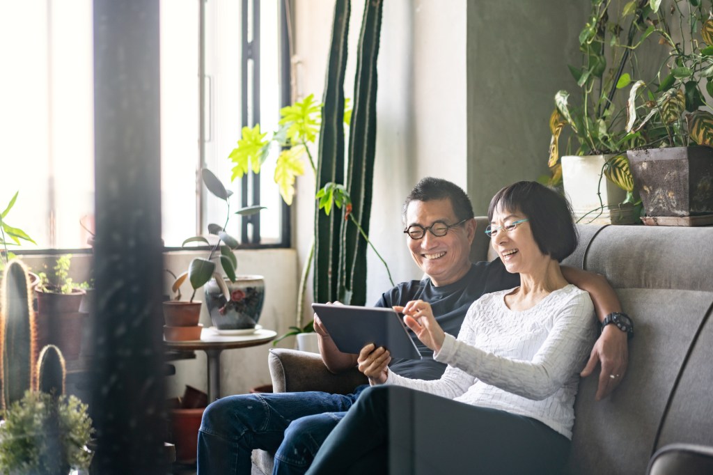 A couple sitting on a sofa and watching a movie on a tablet