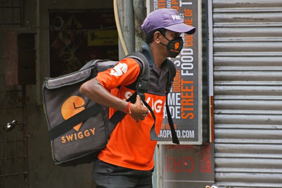 A swiggy delivery boy can be seen in front of a food outlet
