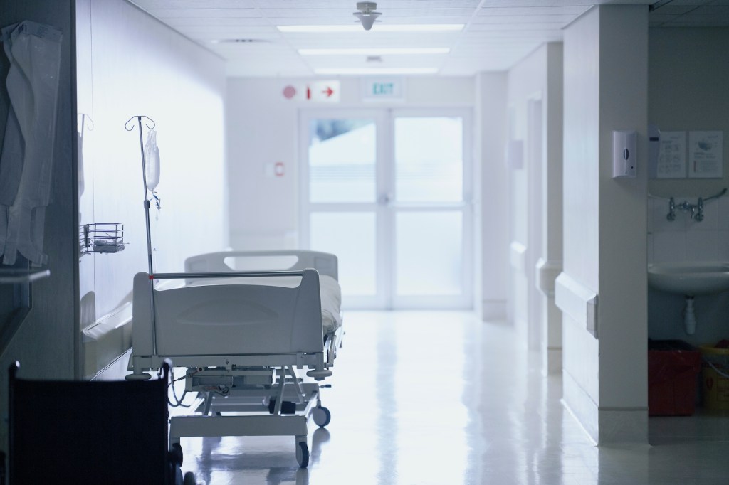 Empty hospital bed with intravenous drip in hospital ward