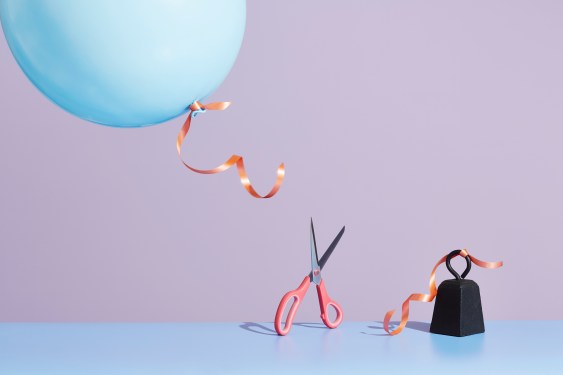 Image of a pair of scissors cutting a string affixed to a metal weight.