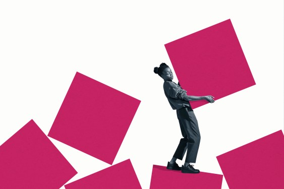 Full length side view of young woman carrying large pink block against white background