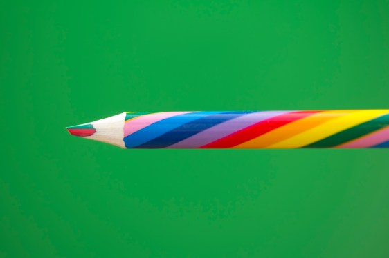 Image of a multicolored pencil on a green background.