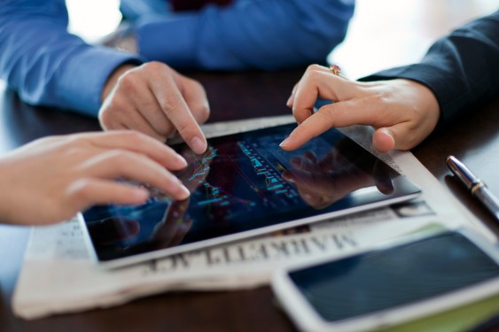 Group of three people looking at data on a tablet.