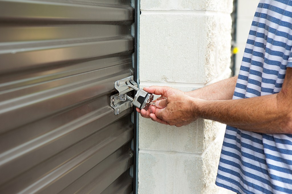 senior male using his key to open a lock at his storage warehouse