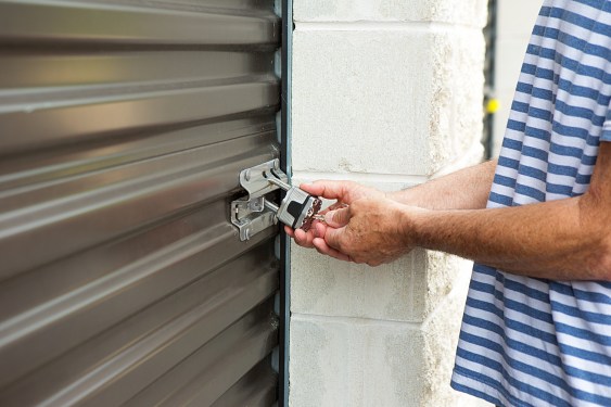 senior male using his key to open a lock at his storage warehouse