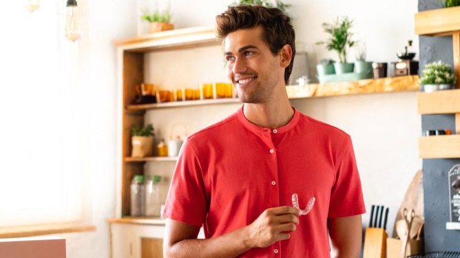 young man holding invisible aligner