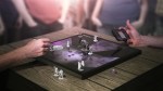People crowd around a flat digital screen with game pieces on it.