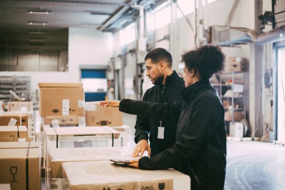 Man and woman in warehouse packing boxes.