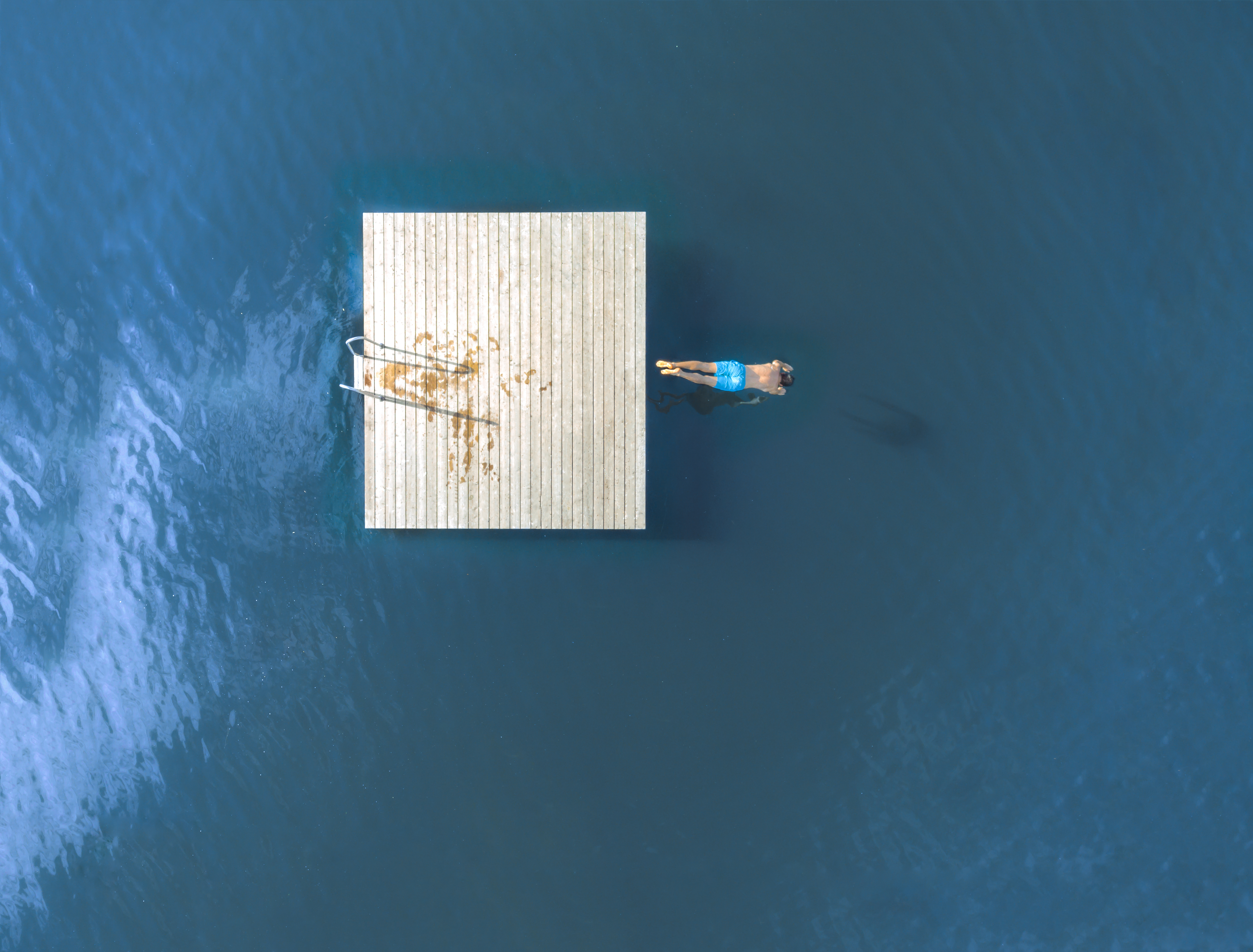 Image of a man jumping from a floating dock into a lake.