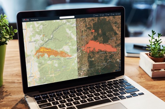 A laptop showing satellite imagery of a wildfire.