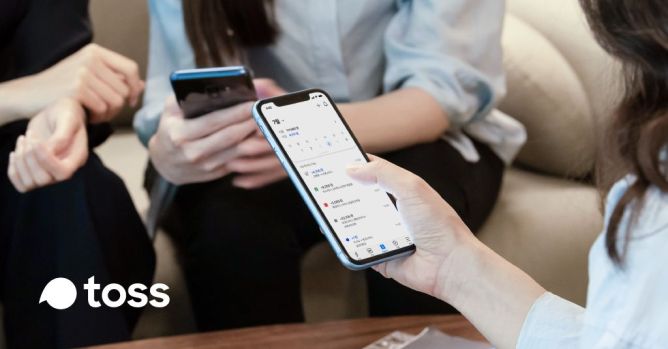 A photo of a person holding a smartphone displaying Toss, the South Korean financial super app