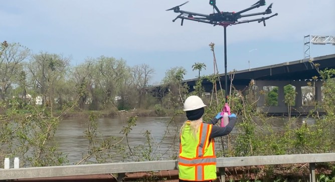 A worker switches the container out of an arm lowered by a drone.