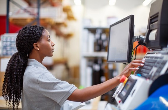 Female worker working on a machine in factory. Woman in uniform operating a machine.