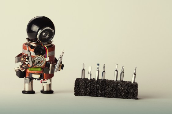 Robot with screwdriver set. Fun toy repair man character, black helmet head and hardware instrument. Macro view, shallow depth of field, gradient background, copy space. (Robot with screwdriver set. Fun toy repair man character, black helmet head and