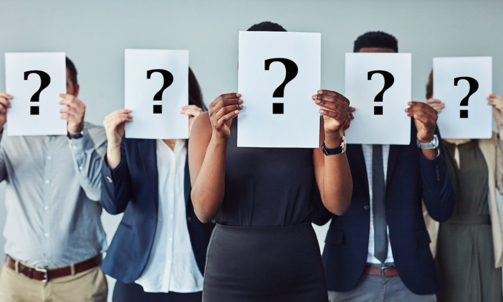 Studio shot of a group of businesspeople holding questions marks in front of their faces