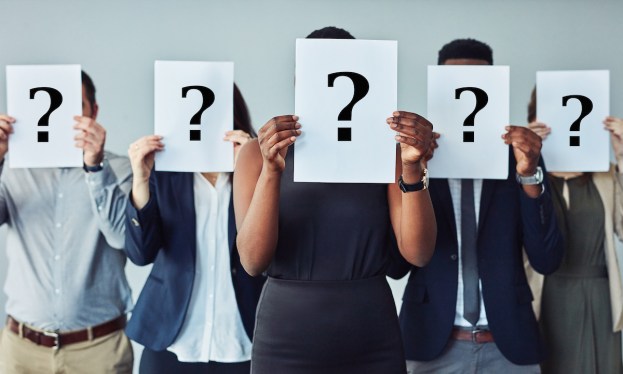 Studio shot of a group of businesspeople holding questions marks in front of their faces