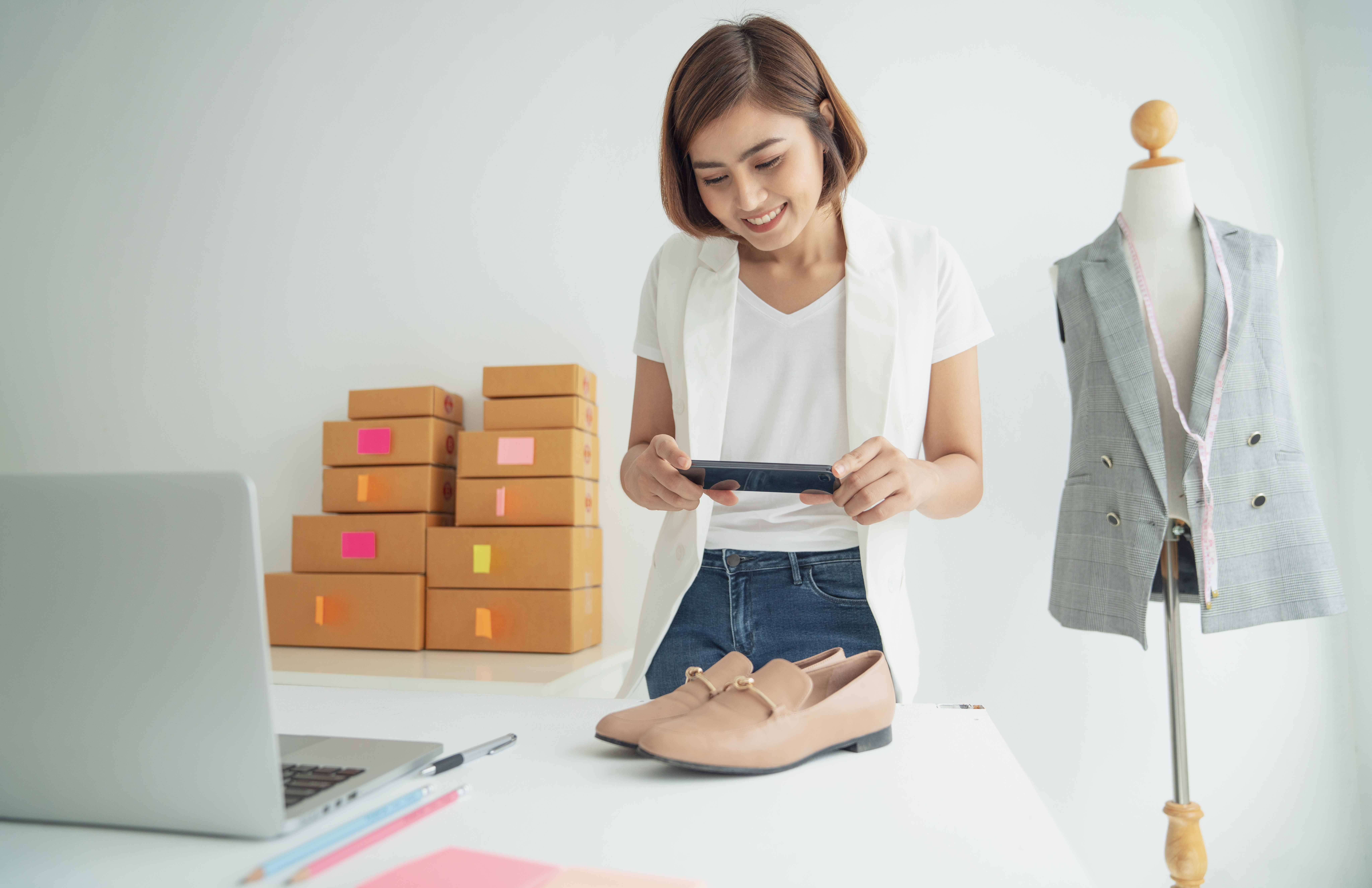 Image of a shop owner taking a photograph of a pair of shoes before mailing to represent how small businesses can compete with Amazon.