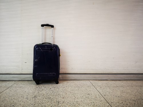 Photo of a black travel suitcase against a roll-up metal gate taken in Chiang Mai, Thailand