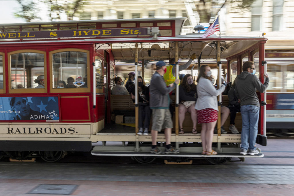 Riders wear protective masks on a cable car in San Francisco, California, U.S., on Tuesday, Aug. 3, 2021. San Francisco and its surrounding counties are reinstating mask requirements in indoor public spaces for all individuals, regardless of vaccination status, after a surge in Covid-19 cases in recent weeks. Photographer: David Paul Morris/Bloomberg via Getty Images