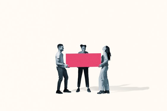 Full length of cheerful young friends carrying large pink block against white background