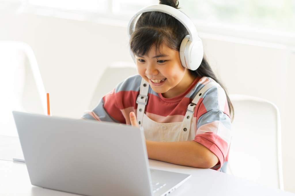 Student with headphones studying at a laptop