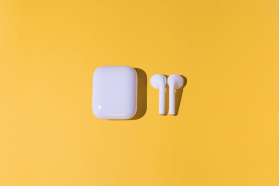 Trendy cordless white headphones on yellow background