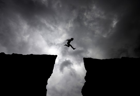 Image of a man jumping over a chasm to represent risk-taking.