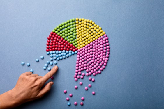 Hand counting pieces of m&ms making up pie chart