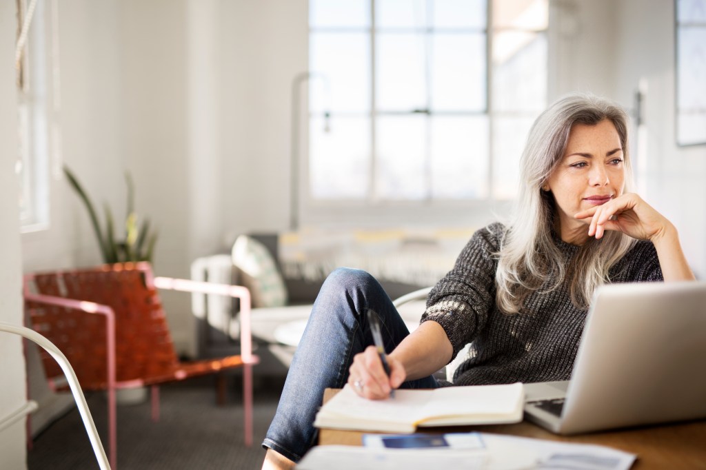 Image of an older woman sitting in front of a laptop working from home.