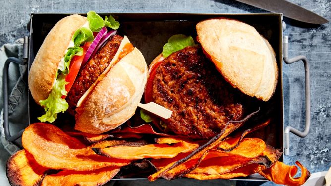 v2Food's plant-based burger in a bun with potato chips next to it.
