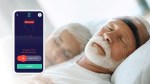 A bearded man wears a Zeit headband in bed, and an app alerts him of abnormal brain activity.