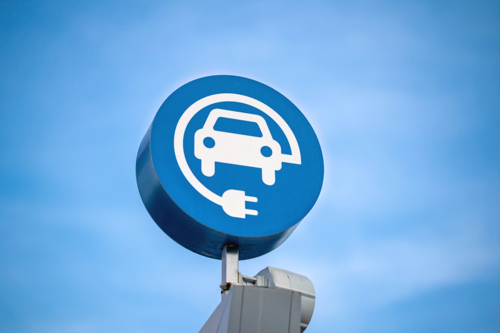 Image of an EV charging sign against a blue sky.