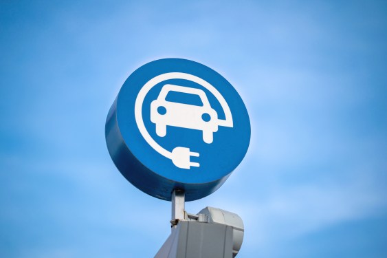 Image of an EV charging sign against a blue sky.