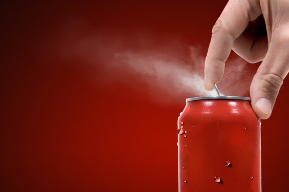 Someone pops the tab on a soda can, releasing a mist/spray