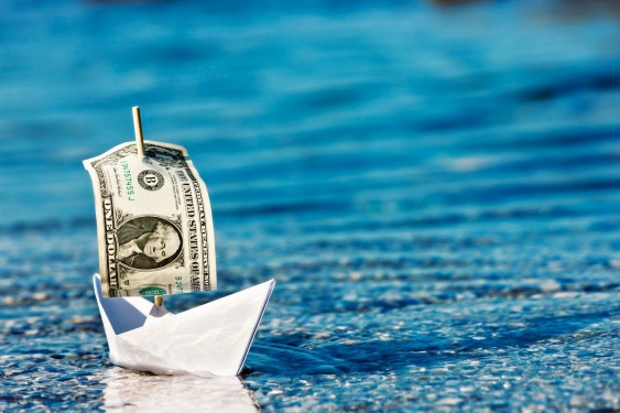 a paper boat with a dollar bill for a sail