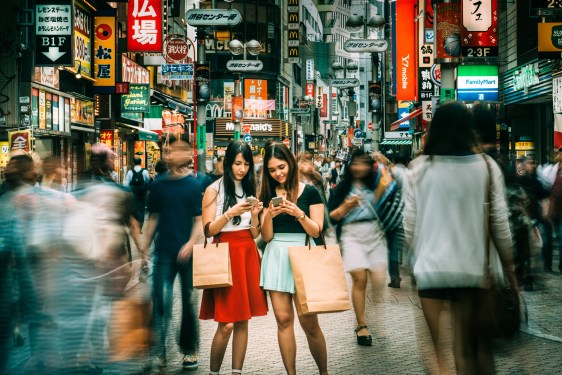 2 women on Tokyo street looking at their mobile phones