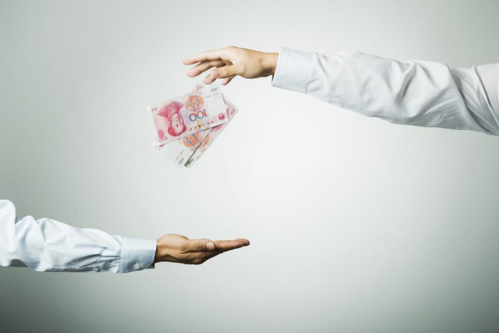 Chinese currency falling from one hand to another.