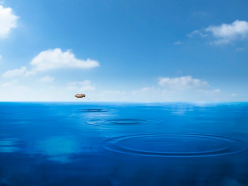 a stone skipping across blue water under a nearly cloudless sky