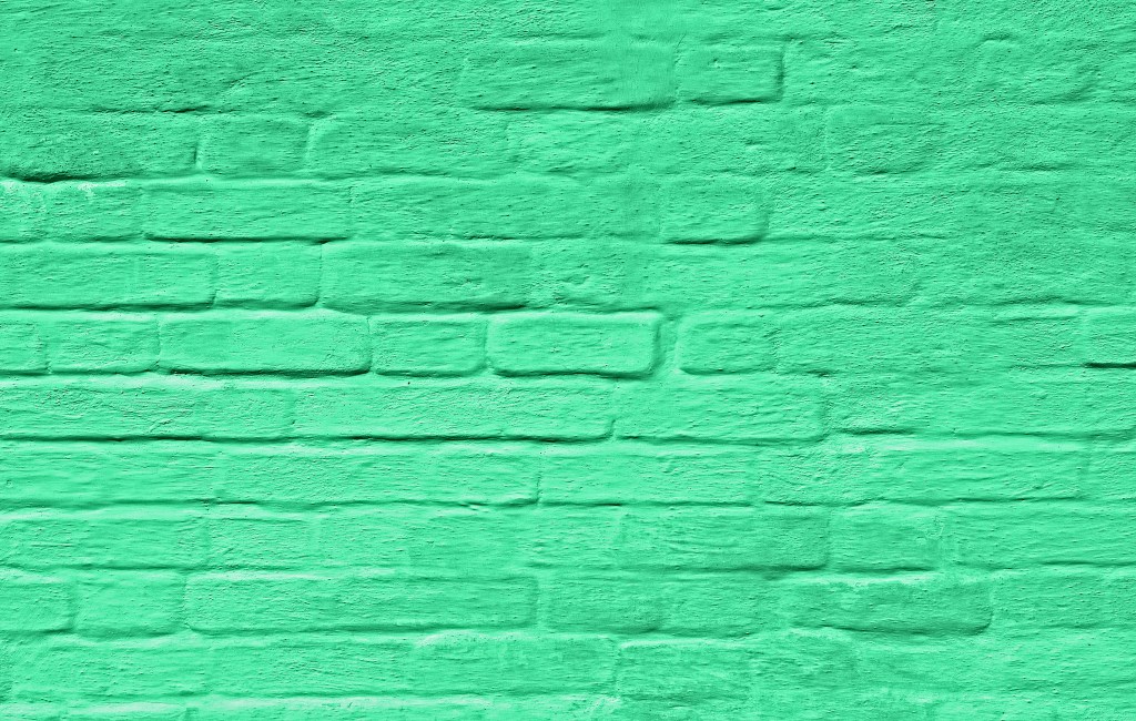 Image of a brick wall painted green to represent greenwashing.