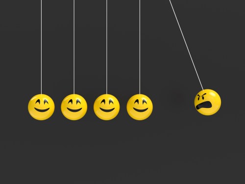A Newton's cradle with an angry emoji ball about to knock into a row of happy emoji balls