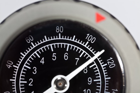 A high-contrast, close up view of pressure gauge dial at 100