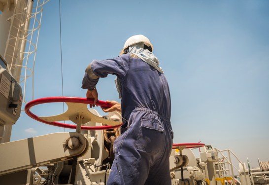 Filipino seafarer unblocking an anchor on a container ship, maritime industry