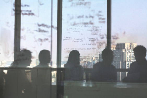 Image featuring silhouette of individuals at a board meeting in office