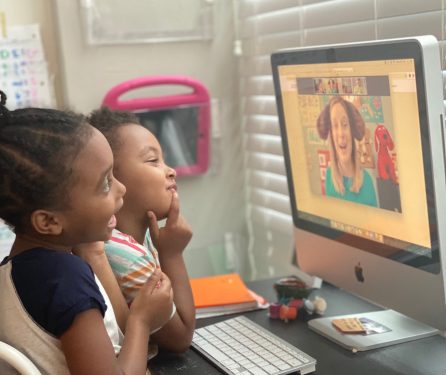 2 kids sitting at a computer monitor