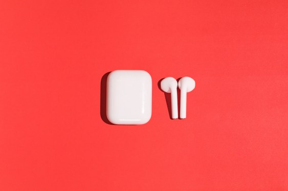 Trendy wireless white headphones on red background.