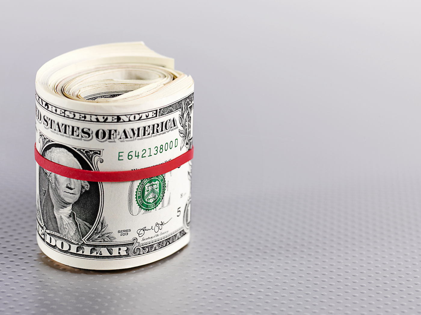 Roll of dollar bills bound with a red rubber band