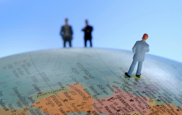Figurine businessmen on top of globe, close-up