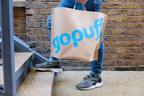 person carrying Gopuff bag up a flight of stairs