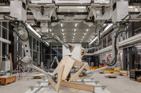 Robot arms hold various sections of the Semiramis structure in a workshop.