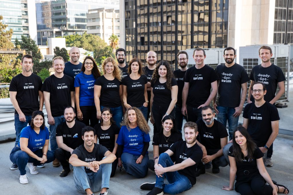 Swimm team employee photo on rooftop in city scape.